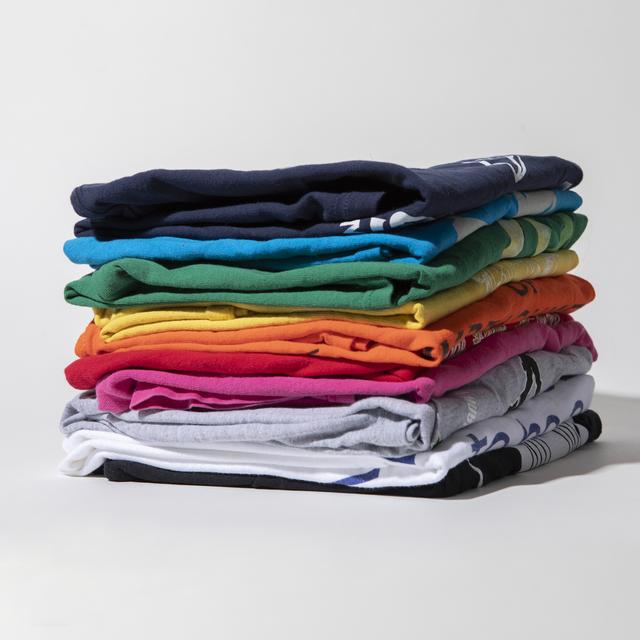Stacks of folded custom summer-camp T-shirts in assorted colors