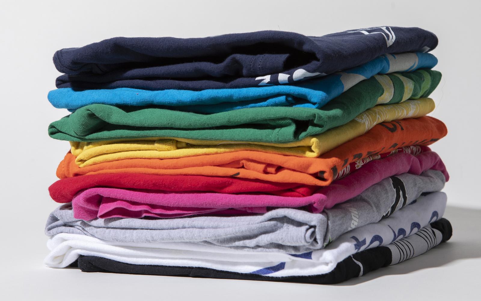 Stacks of folded custom summer-camp T-shirts in assorted colors
